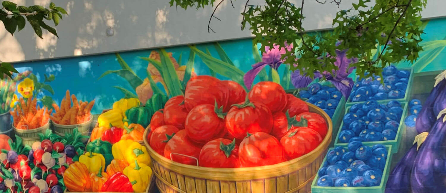 A colorful mural of summer's bountiful produce showing peppers, eggplant, tomatoes, and blueberries. It's painted on a wall at a Farmer's Market in South Haven, Michigan.