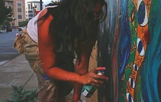 A photo of Visual Artist Nasreen Khan painting a mural in downtown Indianapolis